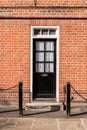 Victorian black external wooden door with glass panels on a classic red brick wall