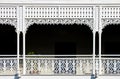 Victorian decorative wrought iron balcony with a plant on it but mostly darkness behind the white painted ornate railings -