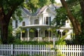 victorian house, with grand porch and white picket fence, surrounded by lush greenery Royalty Free Stock Photo