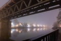 A Victorian steel railway bridge going over a river on a moody, atmospheric foggy winters night. Worcester, River Seven, UK