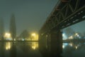 A Victorian steel railway bridge going over a river on a moody, atmospheric foggy winters night. Worcester, River Seven, UK