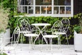 Victorian style white empty metal chairs and tables in outdoor cafe. Wrought iron furniture, old fashion cozy cafe terrace, Royalty Free Stock Photo