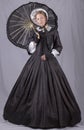 Victorian woman in a black bodice, skirt, parasol and bonnet