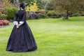 Victorian woman in black dress walking in garden