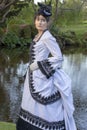 Victorian woman in black and white bustle dress standing in a garden