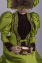 Victorian woman in a green silk outfit drinking a cup of tea