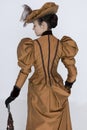 A Victorian woman wearing a bronze and brown silk ensemble