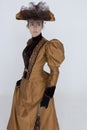 A Victorian woman wearing a bronze and brown silk ensemble