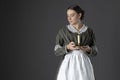 A working class Victorian woman wearing a dark green check bodice and skirt with an apron and holding a candle. Royalty Free Stock Photo