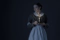 A working class Victorian woman wearing a dark green check bodice and skirt with an apron and holding a candle. Royalty Free Stock Photo