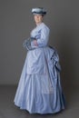 A Victorian woman wearing a pale blue velvet bustle ensemble with a fur muff and hat Royalty Free Stock Photo