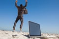 Victorious businessman jumping leaving his laptop