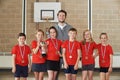 Victorious School Sports Team With Medals And Trophy In Gym Royalty Free Stock Photo
