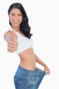 Victorious woman holding her too big pants thumbs up