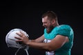 Victory Agressive American football player screaming at the helmet while standing against black background