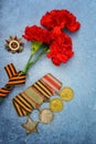 Victory Day.Order of the red star with the Russian inscription Patriotic war and medals on a blue background with red carnations. Royalty Free Stock Photo