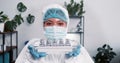 Victory over coronavirus. Cheerful female science lab worker in protection suit shows medical tray with vaccine flasks.