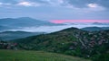 Sunrise and morning mists over the mountain slopes and a small village