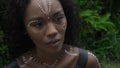 African girl with makeup and painted ethnic lines on the body sitting in a tropical garden