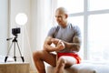 Sportsman sitting near window while making video about biceps