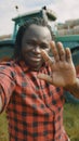 Video call. African farmer waving to the smartphone camere in front of the tractor Royalty Free Stock Photo