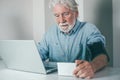 Video call concept. Bearded senior man suffering from hypertension sitting at home talking remotely with doctor on computer webcam