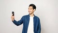 Video call conference, Happy asian man having a video chat on mobile phone while standing on grey background, Asia male talking Royalty Free Stock Photo