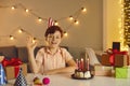 Happy kid at table with birthday cake and presents, waving hand greeting friends at online party Royalty Free Stock Photo