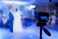 A video camera is filming the dance of the bride and groom. Selective focus.