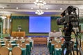 Video camera on tripod have blur screen projector on stage Royalty Free Stock Photo