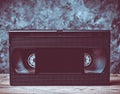 Video cassette close-up on a wooden shelf against a gray concret. Royalty Free Stock Photo