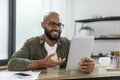 Video conference. Cheerful latino man having web call using digital tablet sitting at desk, talking at webcam in home Royalty Free Stock Photo