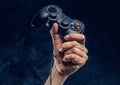 Video game console controller in gamer hand against the background of the dark wall Royalty Free Stock Photo