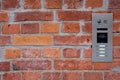 Video intercom on red brick wall background. Modern, luxury, wealthy home security system. Alarm door bell. Safe entrance