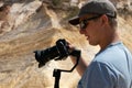 Video maker holding a camera with a stabalizer in the desert