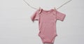 Video of pink baby grow hanging on clothes begs on line with copy space on white background