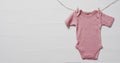 Video of pink baby grow hanging on clothes begs on line with copy space on white background