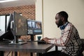 Video production house employee sitting at multi monitor workstation while editing movie frames Royalty Free Stock Photo