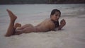 Video of girl lying on the sand with splashing water and moving sensually in slow motion.