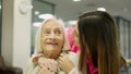 Smiling nurse kissing and embracing a senior woman in geriatrics