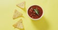 Video of tortilla chips and salsa dip on a yelllow surface