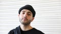 Portrait of bearded young man with cap on his head looking into the camera with pride in slow motion