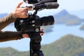 Videographer holding the video camera on a tripod on top of the Royalty Free Stock Photo