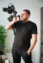 Videographer man with camera mounted on gimbal stabilizer equipment indoors. Royalty Free Stock Photo