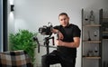 Videographer man with camera mounted on gimbal stabilizer equipment indoors. Royalty Free Stock Photo