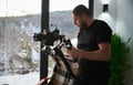 Videographer man with camera mounted on gimbal stabilizer equipment indoors. Royalty Free Stock Photo