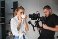 Videographer man shooting footage with female model, using camera. Royalty Free Stock Photo