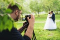 The videographer shootes the marrieds in the garden in the summer