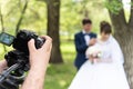 The videographer shootes the marrieds in the garden in the summer