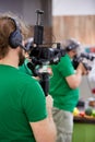 Videographer shooting a film or a television program in a studio with a professional camera, backstage Royalty Free Stock Photo